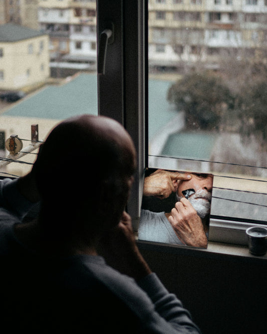 Bald man applying shave cream in a bathroom mirror, morning light | Hardwick & Co. daily scalp moisturiser routine