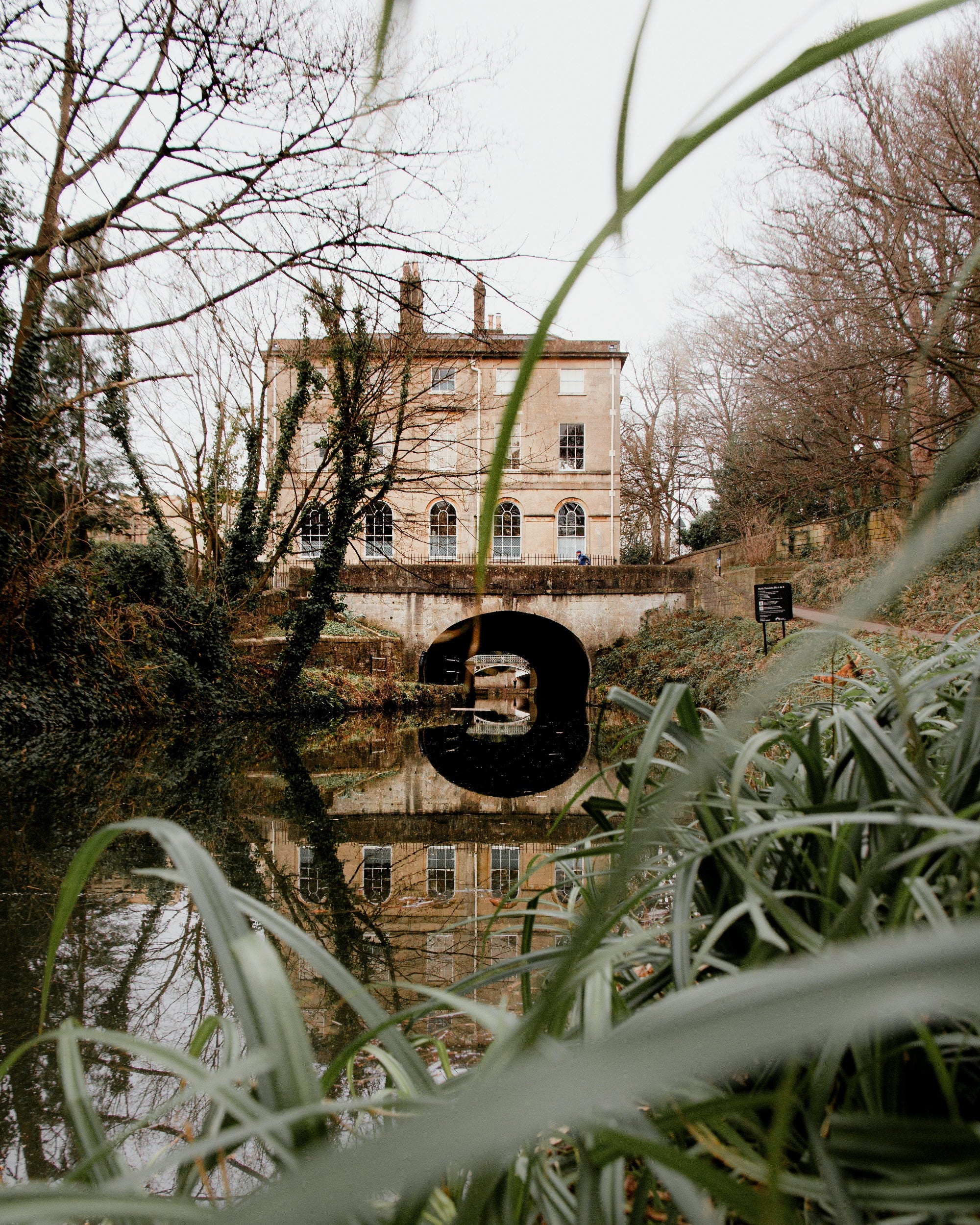 House reflected in water with trees and grass in foreground