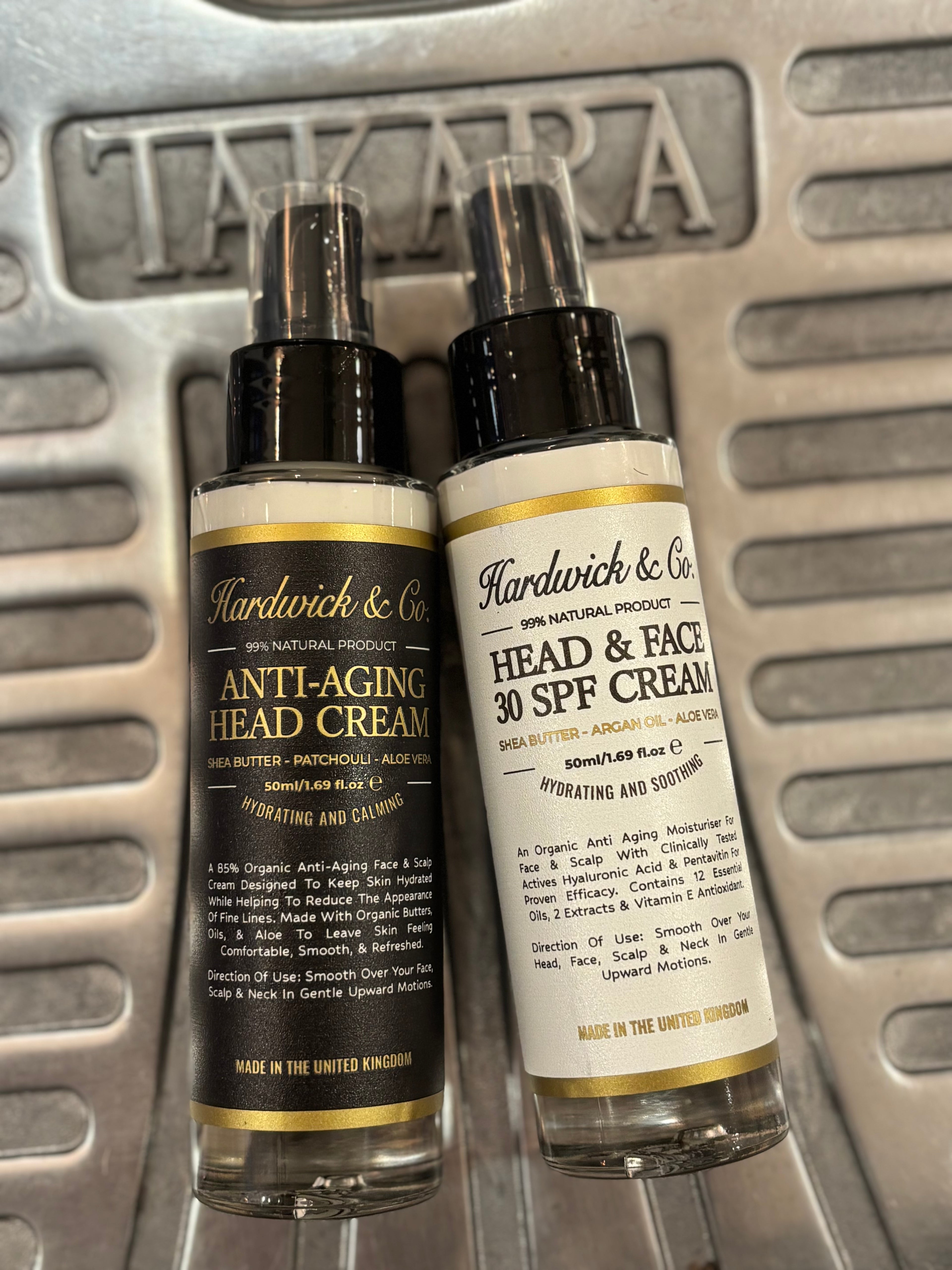 Two bottles of Hardwick & Co skincare products on a metallic surface.